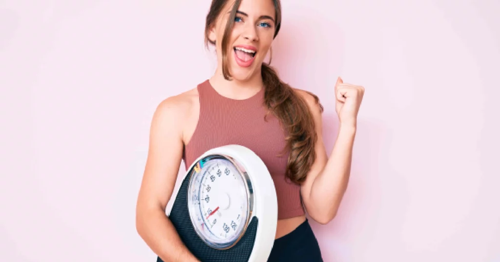 woman in activewear holding a scale celebrating her weight loss success in Chesterfield, MO